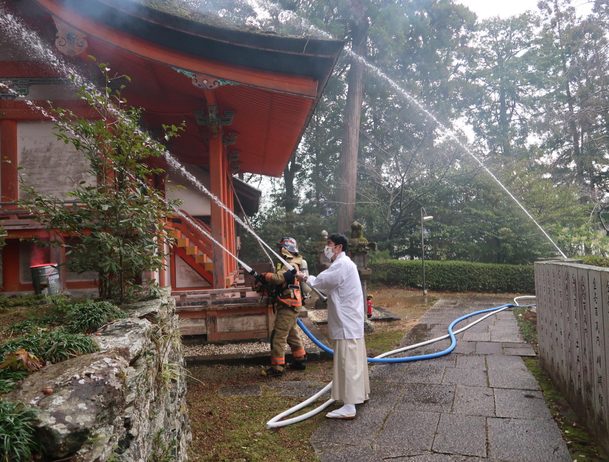 消防隊員と宮司による放水の様子